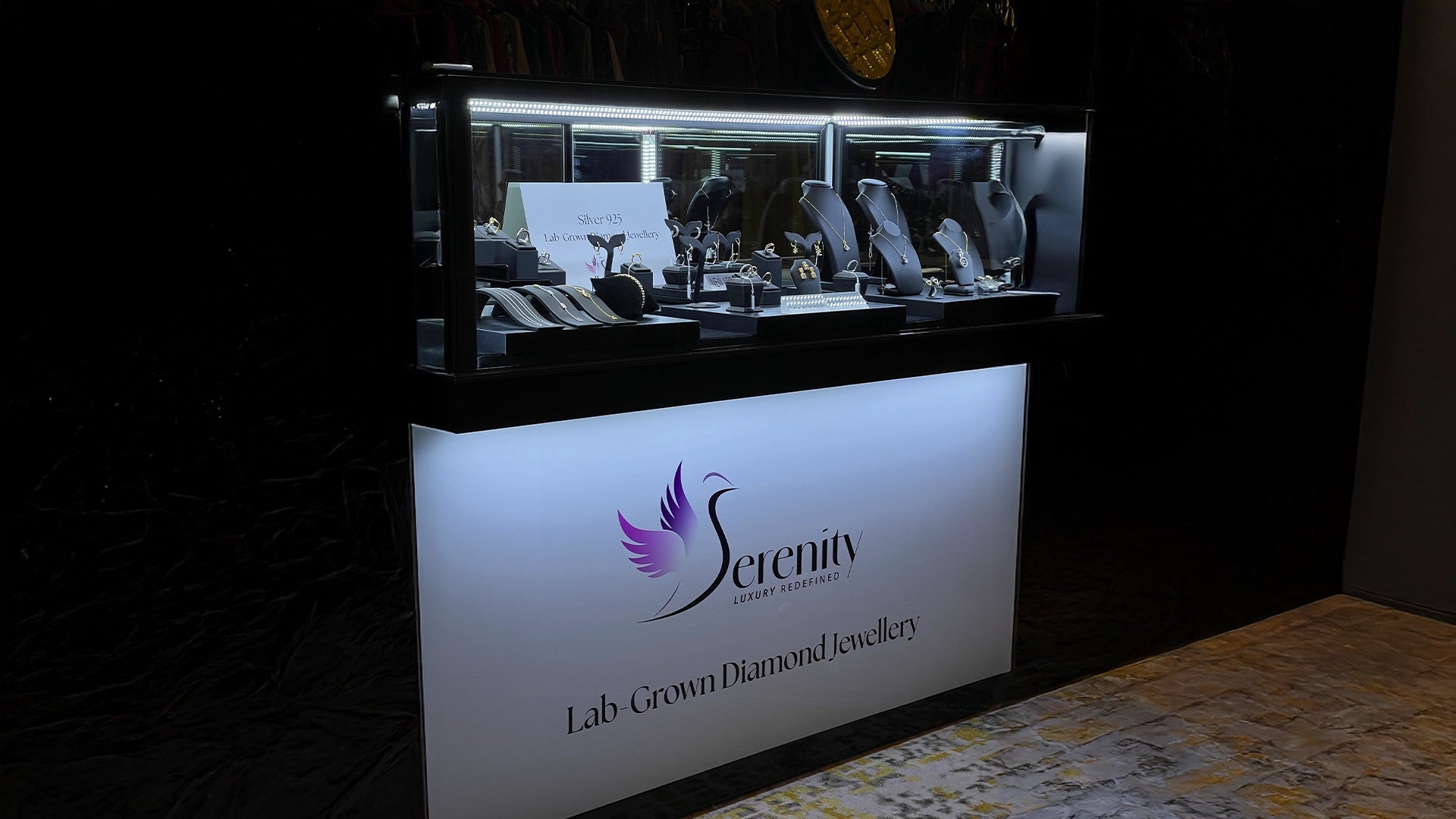 Display case with jewelry and 'Serenity' counter booth on a dark background